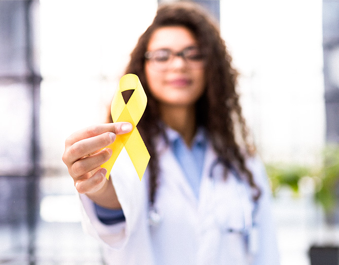 Image of a female medical staff member holding up a yellow ribbon.