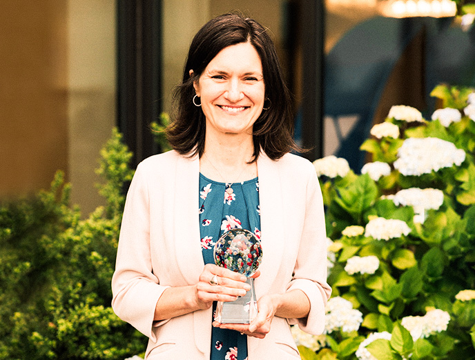Image of Kristin Meadows smiling in an outdoor setting with the Philanthropy Volunteer of the Year award in her hands.