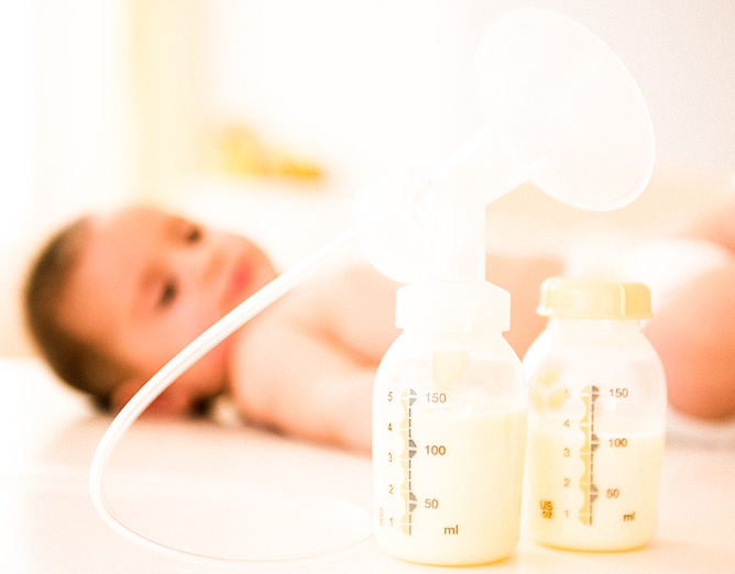 Image of baby next to two bottles of breast milk.