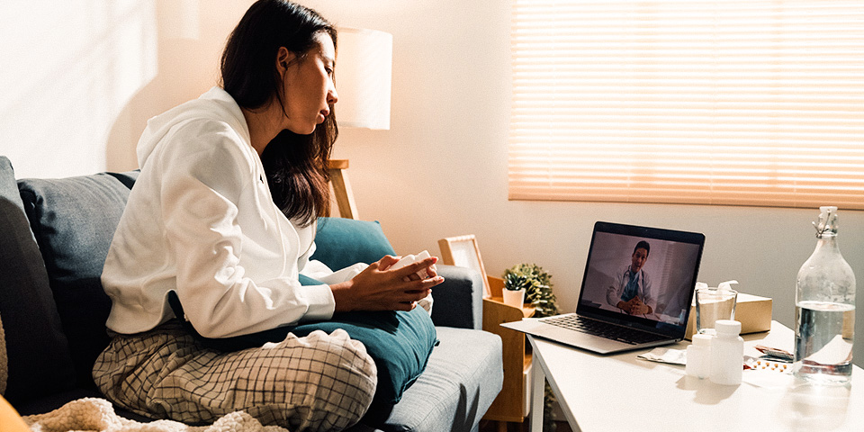 Image of a woman sitting on a couch using a laptop for virtual care.