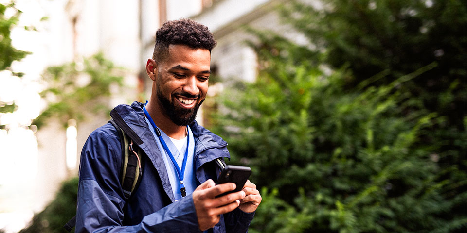 Young black man viewing content on mobile phone in outdoor setting