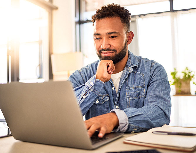 Male sitting at desk viewing a laptop screen