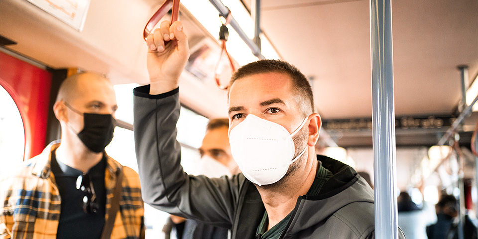 Adult male riding public transportation wearing a face mask