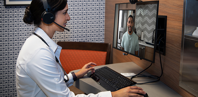 Adult female medical professional wearing a headset is on a video call with an adult male